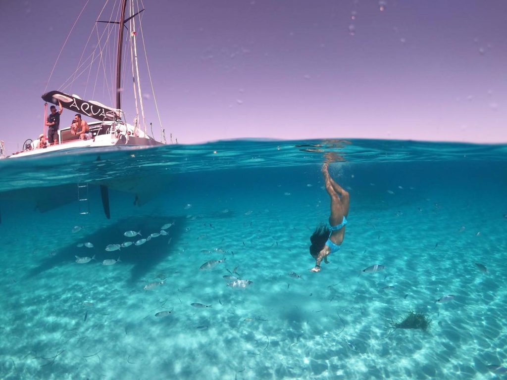 Girl freediving from the submerged part of a catamaran in Asinara Island